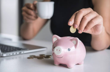 woman putting money in piggy bank for marketing budget