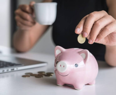 woman putting money in piggy bank for marketing budget